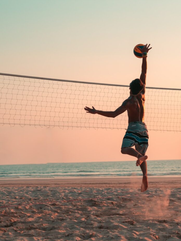 Photo by Colton Duke man playing beach volleyball during daytime